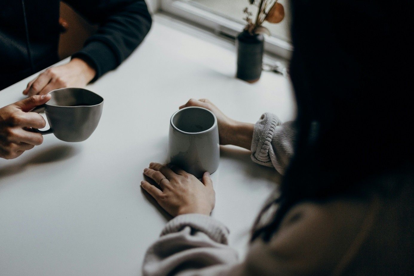 Twee mensen met een kop koffie in gesprek aan tafel