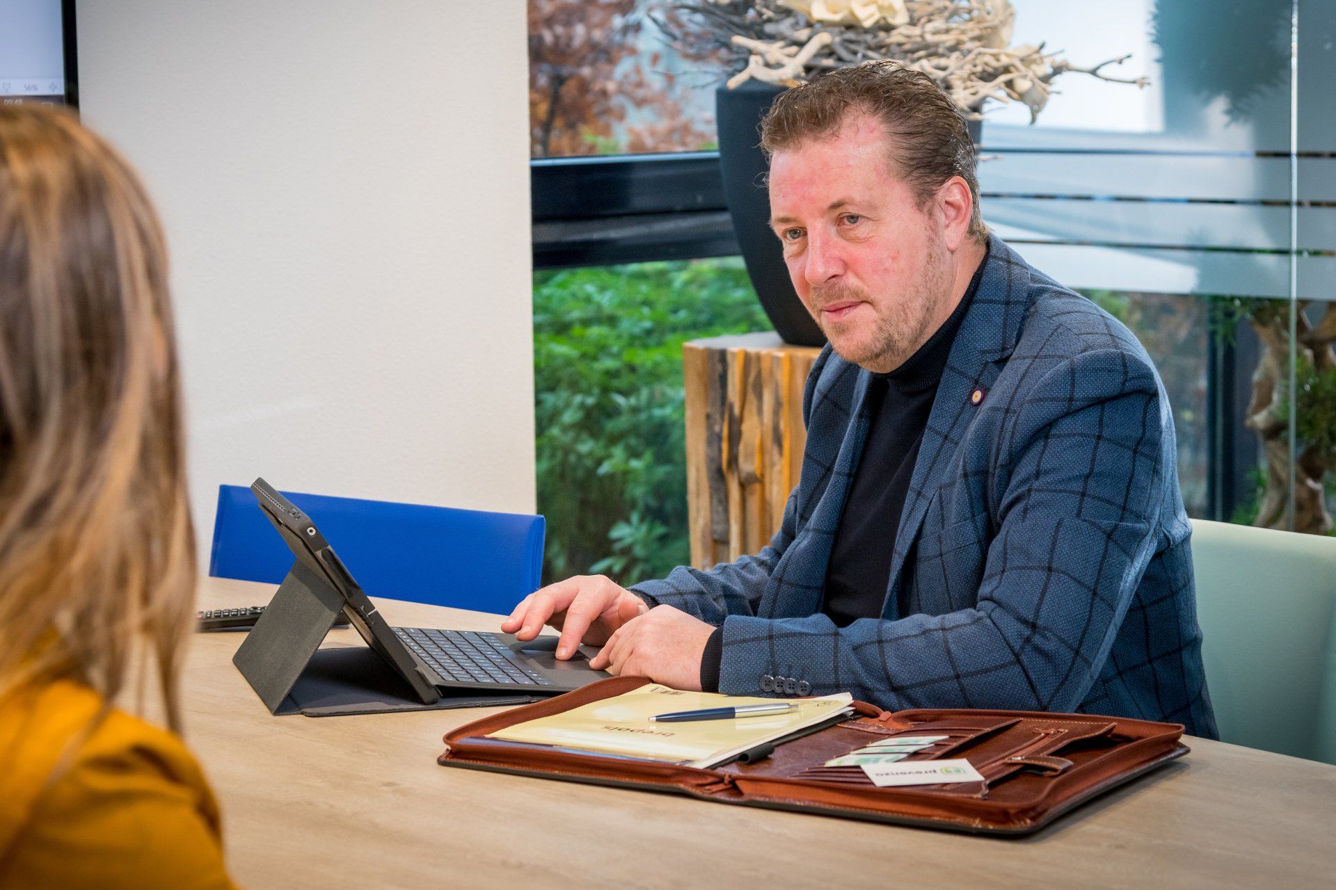 Een man werkt op zijn laptop aan een overlegtafel