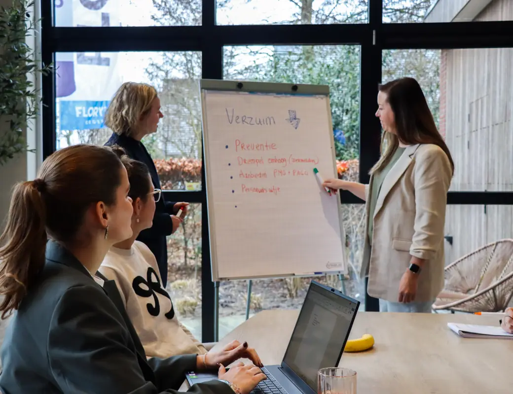 Twee casemanagers van Prevenzo bespreken de verzuimaanpak met collega&rsquo;s aan de vergadertafel