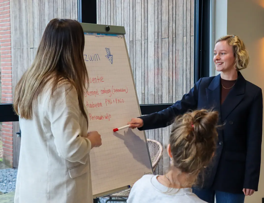Uitleg bij de flipover tijdens een verzuimtraining, met een deelnemer op de voorgrond