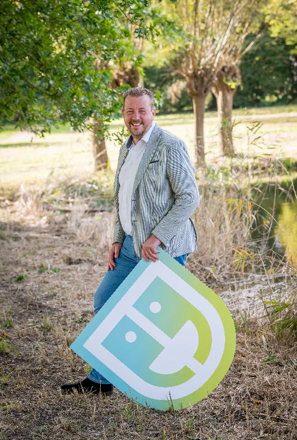 Medewerker van Prevenzo met het merkschild, buiten bij een sloot met wilgen